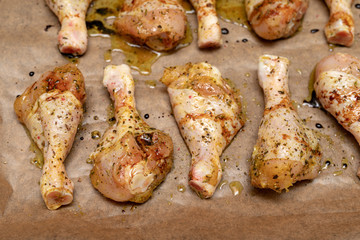 Raw chicken legs sprinkled with spices. Poultry meat prepared for baking.