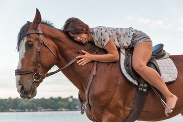 horse and young beautiful woman on river beach closeup