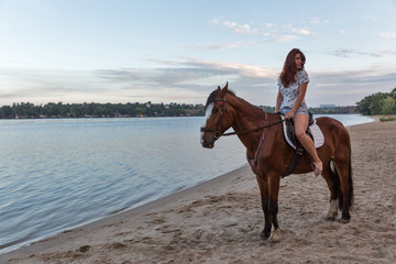 horse and young beautiful woman on river beach