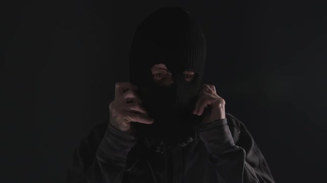 Desperate man puts balaclava mask on at night, looking spooky and threatening