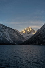 lighted snowy mountain peak thaneller at lake plansee in winter