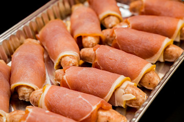 Sausages wrapped in bacon ready for oven baking