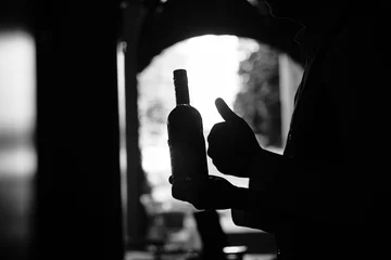 Poster Bottle of wine in a hand at the dark tunnel © ruslanseradziuk