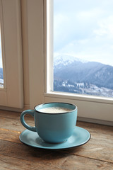 Hot drink near window in room with view of winter mountain landscape