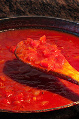 CUCHARA DE MADERA CON SALSA DE TOMATE EN LA SARTEN