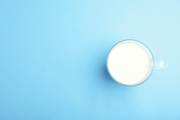 Cup of fresh milk on color background, top view. Space for text