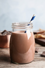 Jar with tasty chocolate milk on wooden table. Dairy drink