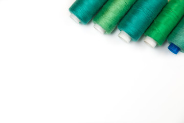 Accessories to a hobby of sewing of clothes: a set of different strings of green color on a white...