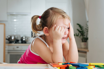 Charming preschooler playing with wooden constructor. Little girl playing with connecting pieces