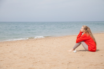 Fototapeta na wymiar a woman sits at a deserted sandy beach looking at sea