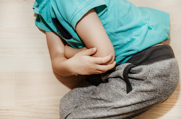 A little boy, the child is lying on the ground and holding his stomach. Baby's medication and...