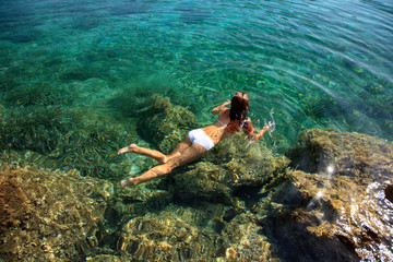 Young woman swimming in transparent sea water