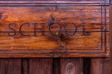 Wooden sign with the school inscription engraved on it.