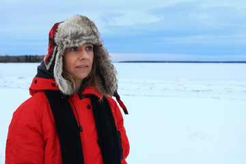 Fototapeta na wymiar Portrait of a woman wearing a fur aviator hat and a red jacket in the winter weather