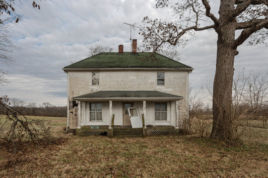 Vintage farmhouse abandoned with barren tree
