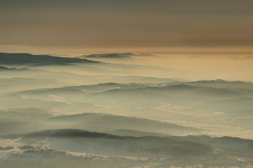 Aerial view of gentle slopes in winter haze at dawn in Gorce, Beskid Sadecki and Zywiecki ranges from Babia Gora peak, Beskidy Zachodnie mountains Western Carpathians Podhale Malopolska Poland Europe