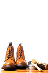 Mens Brogues Boots In Line With Cleaning Accessories on Shiny Table.Against White.