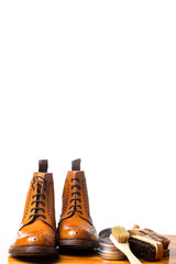 Mens Brogues Boots In Line With Cleaning Accessories on Shiny Table.Against White Background.