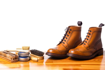 Mens Brogues Boots In Line With Cleaning Accessories on Shiny Table.Against White.