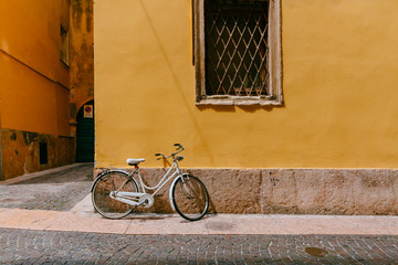 White bike parked agaisnt yellow wall in the street of Verona, Italy