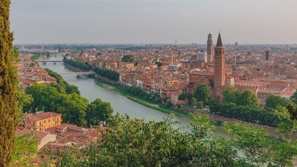 Fototapeta na wymiar Adige river by the historical center of Verona, Italy, with the bell tower of the Church of Santa Anastasia and the Lamberti Tower