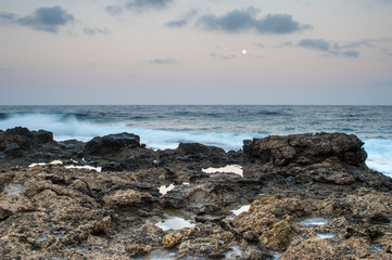 Fototapeta na wymiar Morning sunrise on rocky sea coast, lit by the moon