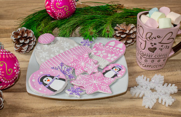 New year preparations. Gingerbread, penguins, mittens and hats with asterisks and a mug of marshmallow on a wooden background. Branches of fir and ornaments. Festive Christmas background.