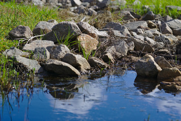 Piles of stones near blue water in sunny day