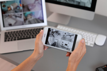 female security guard monitoring home cameras using smartphone indoors, closeup