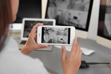 female security guard monitoring home cameras using smartphone indoors, closeup
