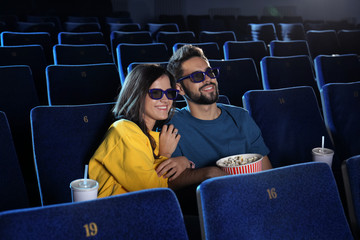 Young couple with popcorn watching movie in cinema theatre