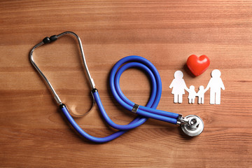 Flat lay composition with heart, stethoscope and paper silhouette of family on wooden background. Life insurance concept