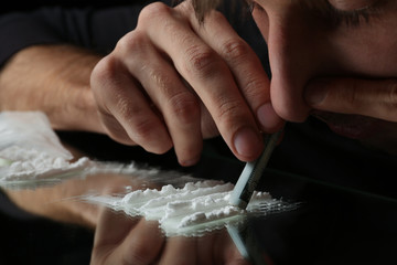 Drug addict taking cocaine at table, closeup view - obrazy, fototapety, plakaty