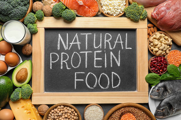 Chalkboard with written text Natural Protein Food among products, top view