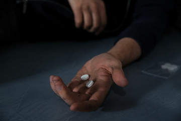Young addicted man holding drugs, closeup view