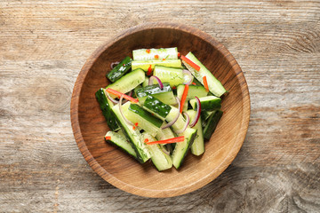 Plate with delicious cucumber salad on wooden background, top view