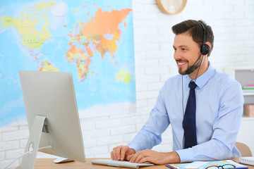 Male consultant working with computer in travel agency