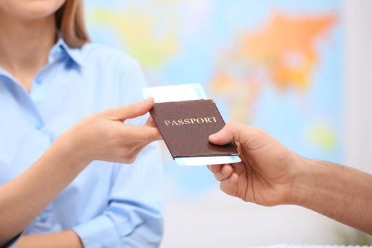 Female manager giving passport with ticket to client in travel agency