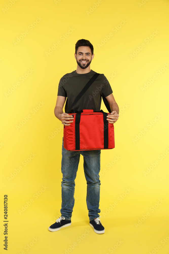 Poster Young courier with thermo bag on color background. Food delivery service