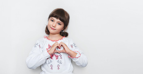 Little Ukrainian girl makes a heart shape with her hands. Love to motherland. Patriotic feelings.