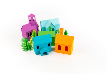 Rainbow house glued out of paper stands in the multicolored forest.