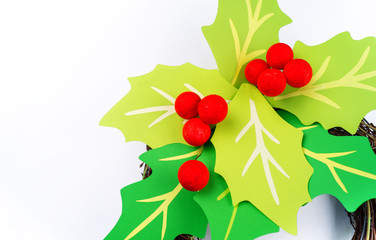 Flower holly made of paper crafts. Round wreath on the door with Christmas leaves.