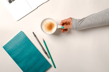 Work space with laptop, turquoise notebook and female hands holding cup of coffee. Flat lay, top...