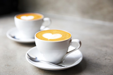 Obraz na płótnie Canvas Two white cups of tasty cappucino with love art latte. Valentine's concept.