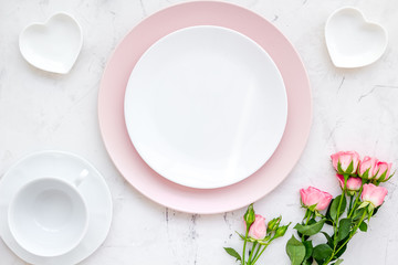 set-up table with plates, heart-shaped saucer and flower on white background top view mock-up