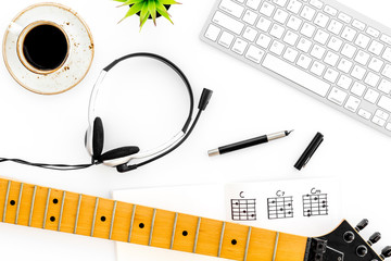 musician work set with guitar neck, keyboard, coffee and headphones white table background top view