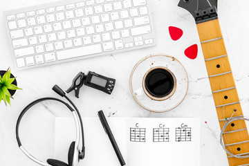 musician work set with guitar neck, keyboard, coffee and headphones marble table background top view