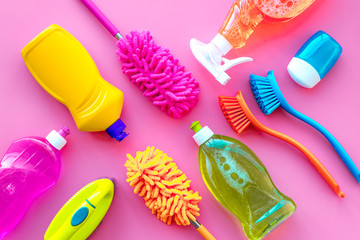 Housecleaning with detergents, soap, cleaners and brush in plastic bottles on pink background top...