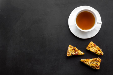 Dessert for evening tea. Cup of tea, fresh homemade cookies on black background top view copy space