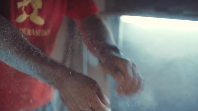SLOW MOTION: An experienced shaper cleans the dust off his hands after finishing the cutting job on a new surfboard.